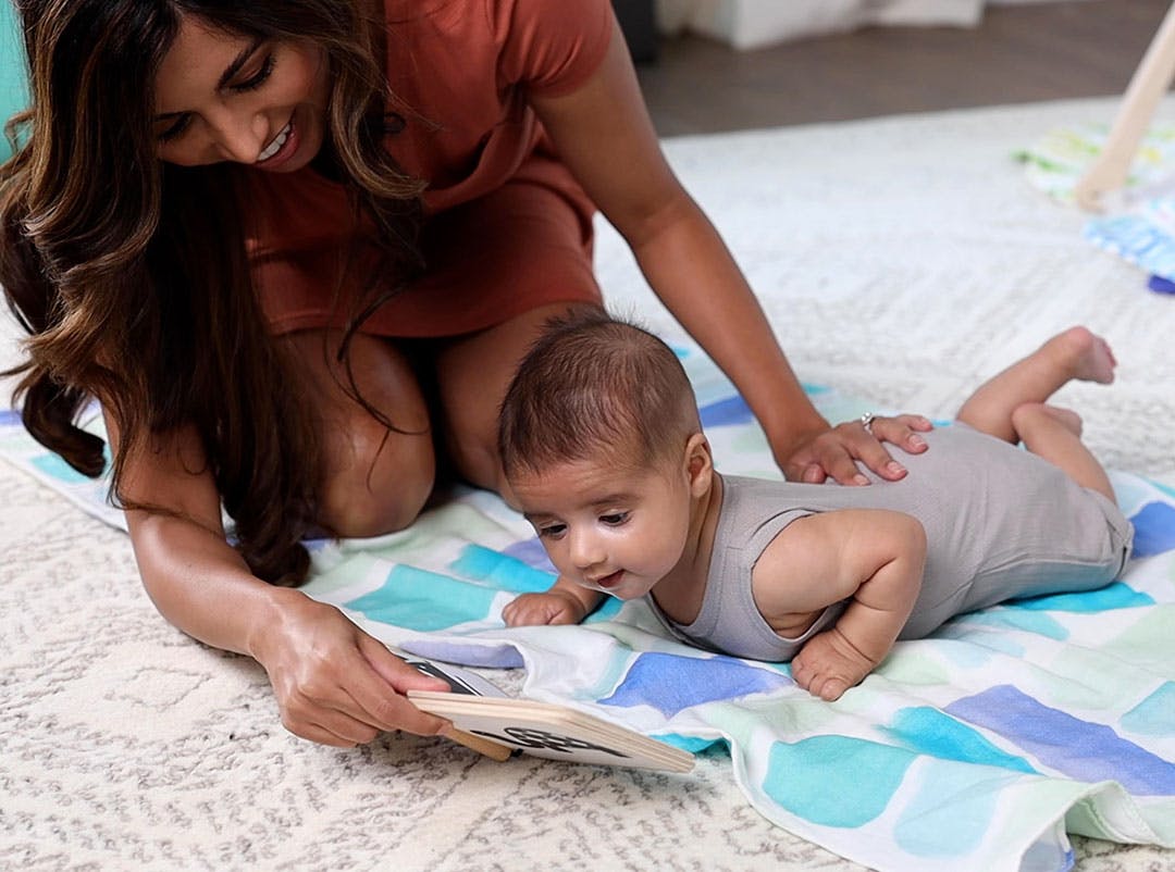 Baby doing Tummy Time while looking at the Wooden Book by Lovevery